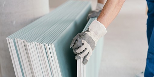 Builder taking a sheet of chip board cladding